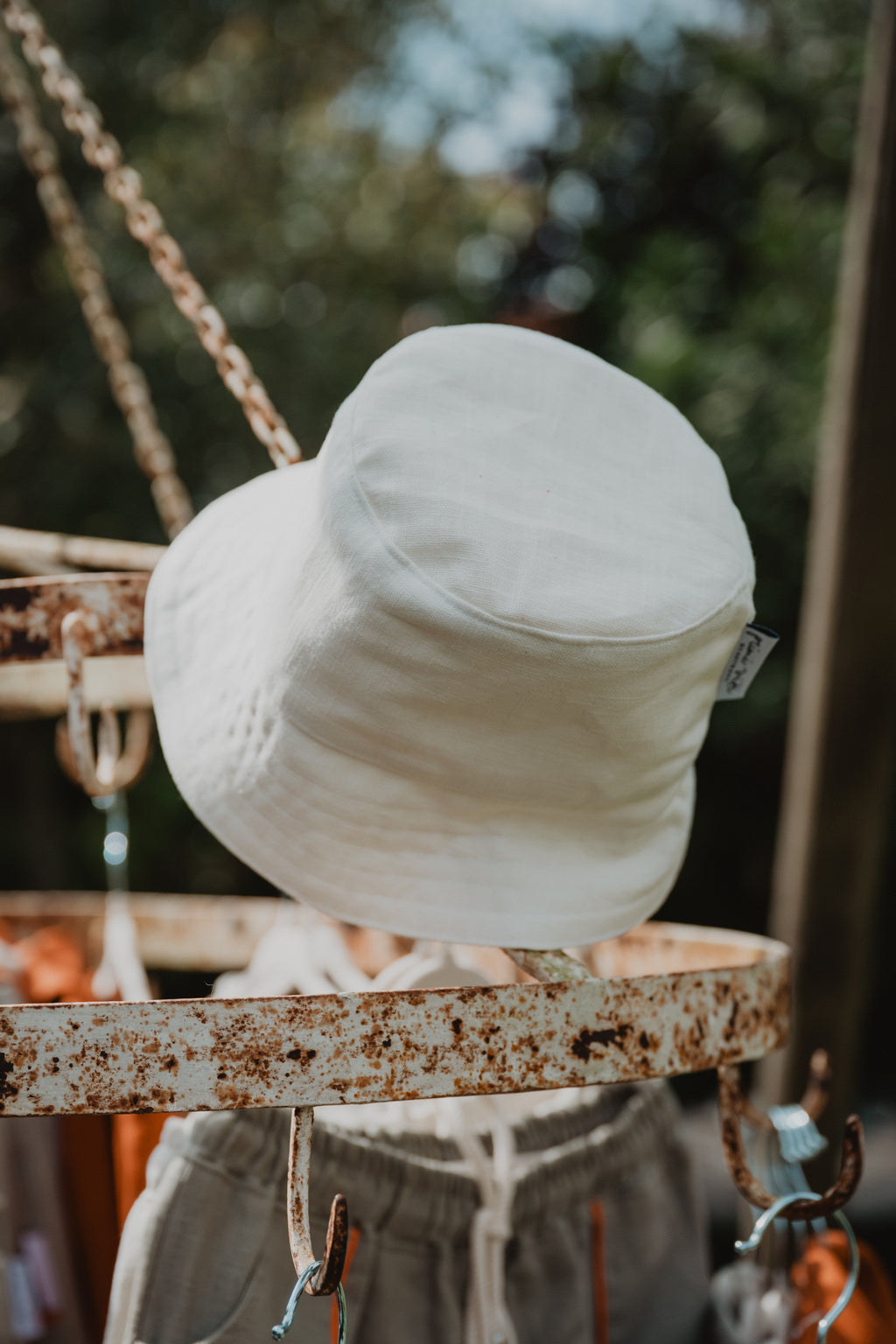 Cappellino da pescatore da bambino del brand Primi Vizi color bianco panna appeso a una struttura metallica 