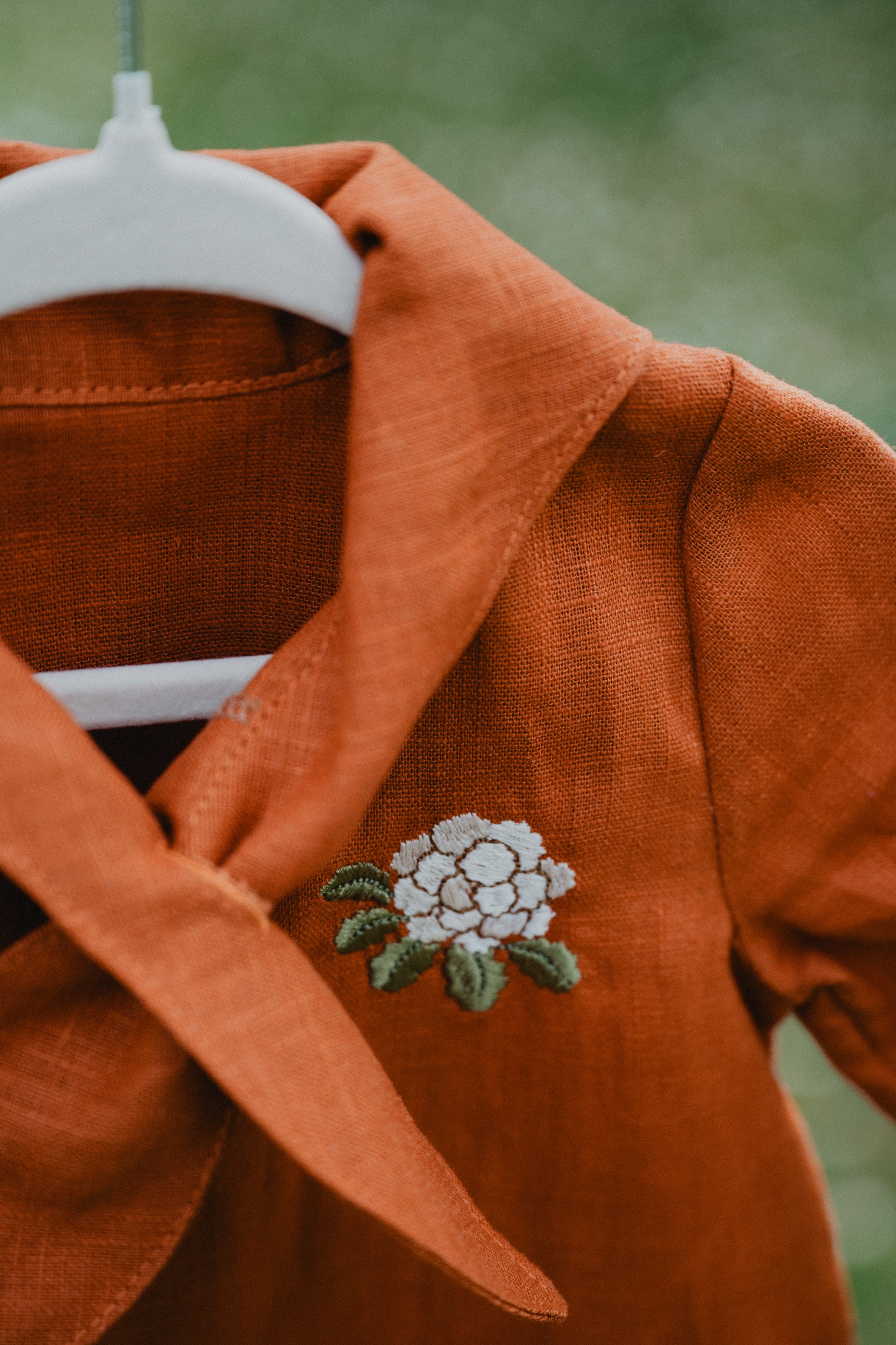 Dettaglio tutina in lino cognac con ricamo floreale sul petto e collo