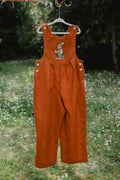Salopette unisex in lino lavato arancione appesa, con pettorina e bottoni