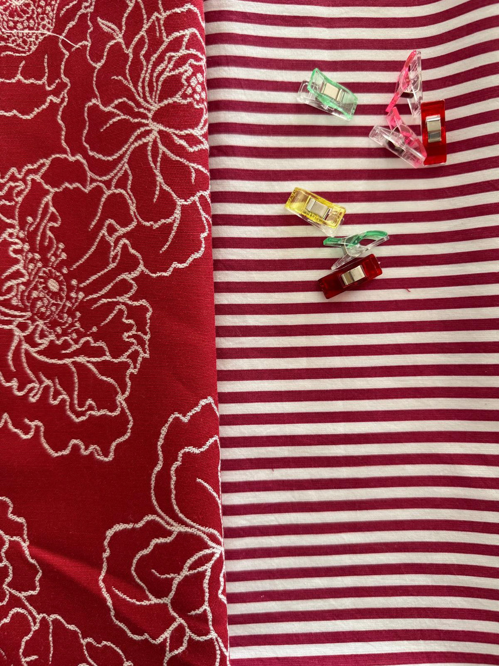 Tessuto rosso con ricami chiari e sfondo a righe rosse e bianche