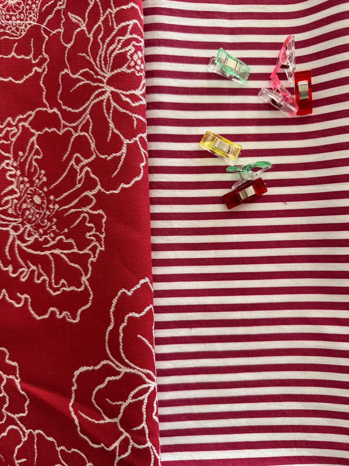 Tessuto rosso con ricami chiari e sfondo a righe rosse e bianche