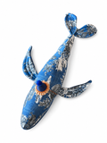 Giocattolo balena in tessuto blu, fantasia bianca e arancione, occhi neri.