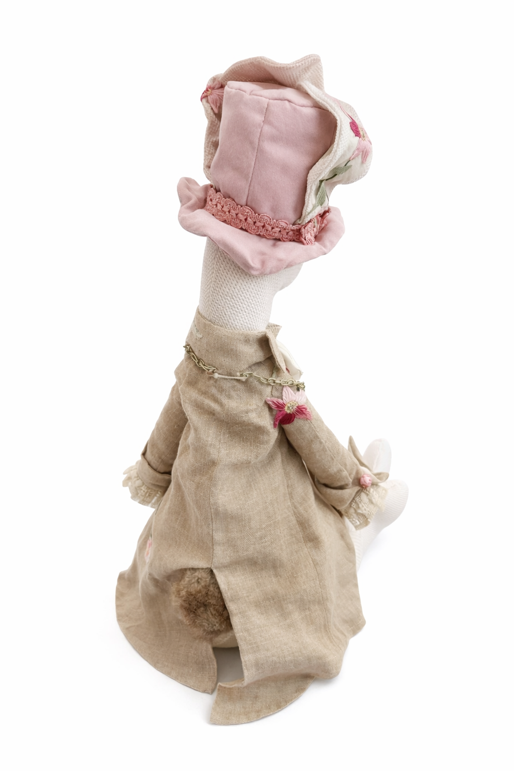 Coniglio gigante beige con gilet e cappellino rosa, visto di lato