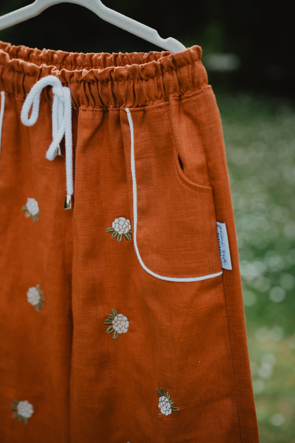 Pantaloni baggy cognac con tasche applicate e coulisse bianca, ricami a margherite