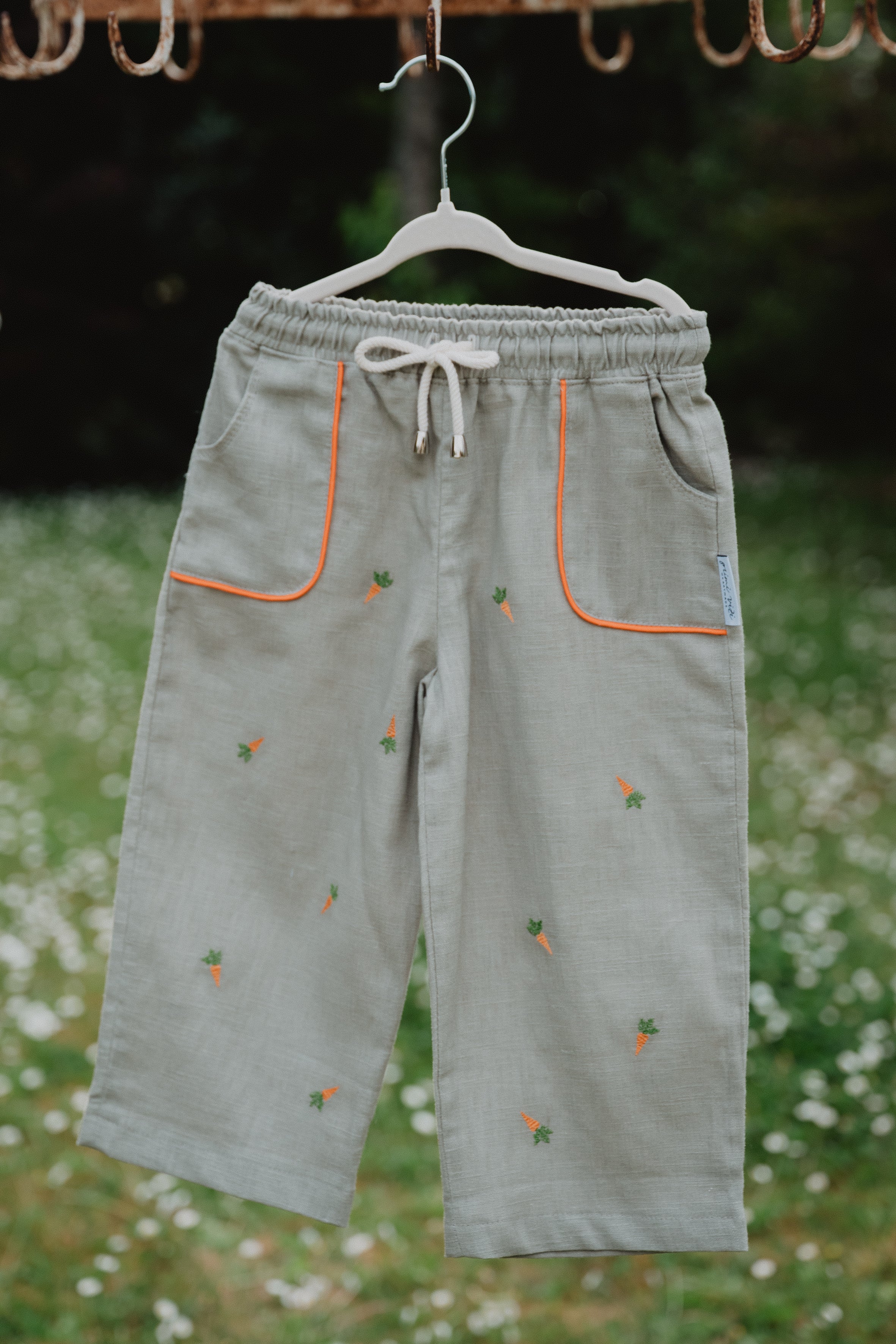Pantaloni baggy in lino lavato chiari con coulisse bianca, tasche arancioni e ricami