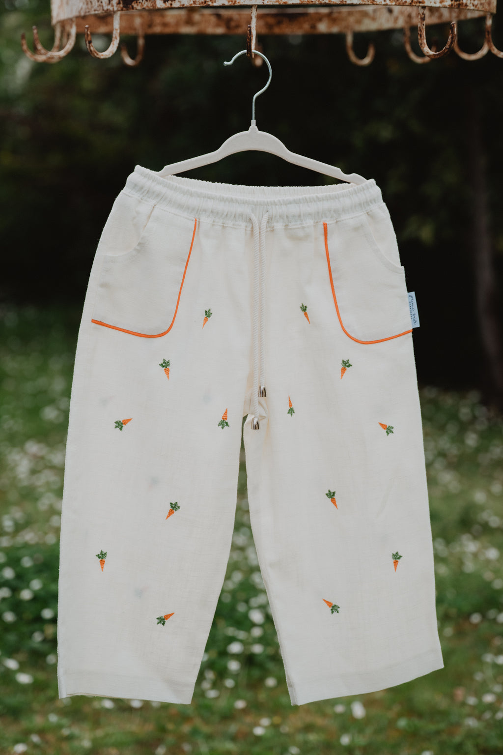 Pantaloni baggy in lino lavato bianchi con tasche arancioni e ricami a carote