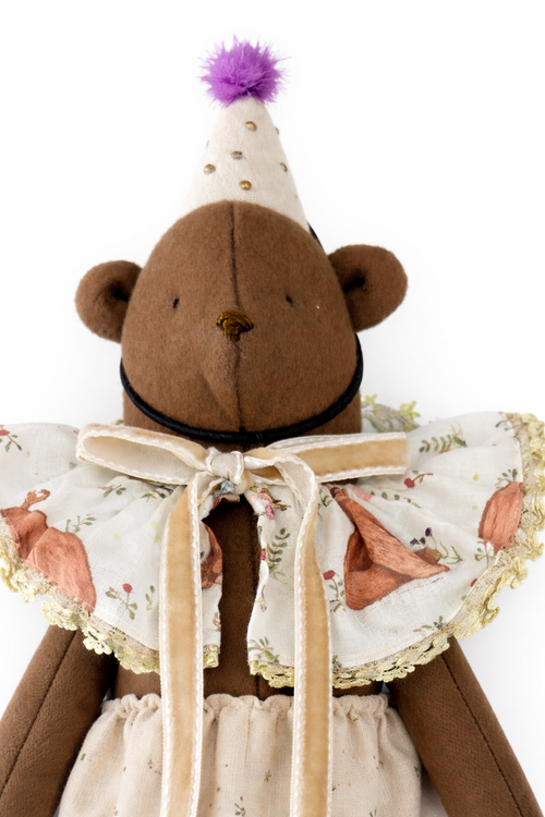 Orsetto di peluche marrone con cappello viola e colletto in tessuto floreale